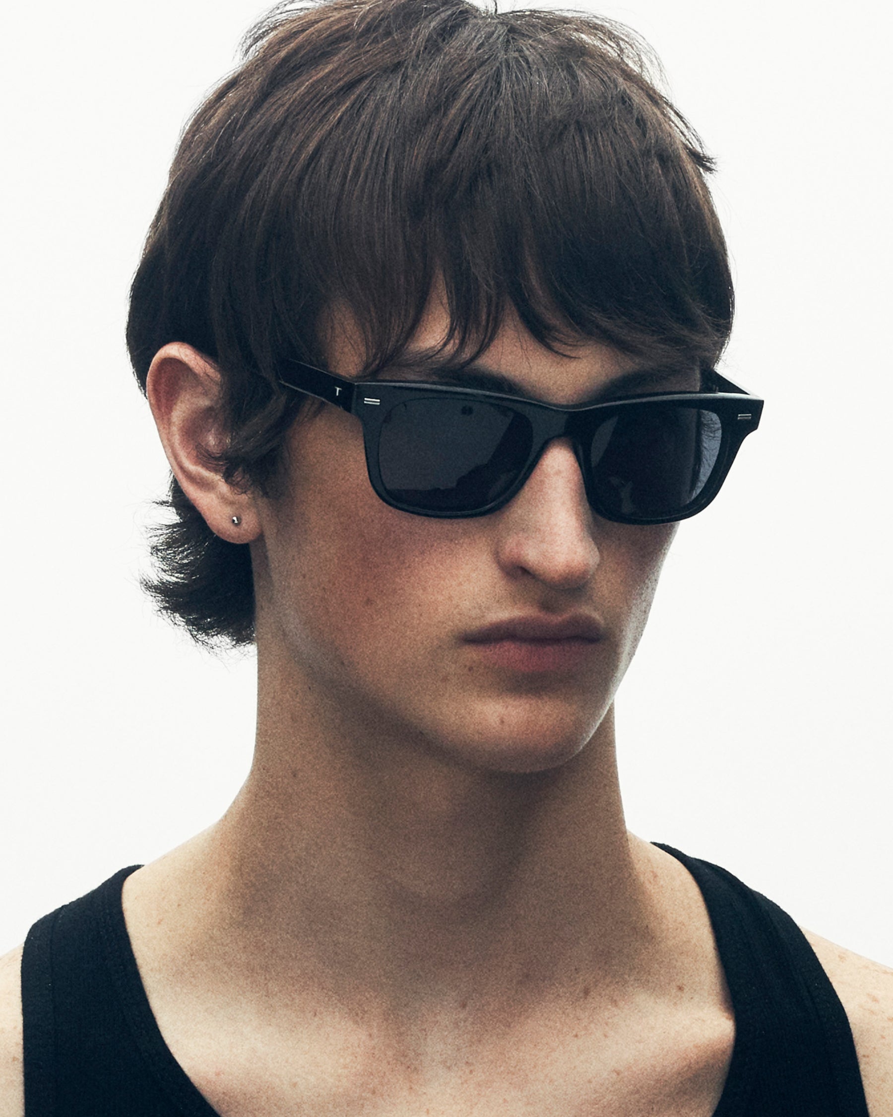 model wearing sunglasses. he is looking off to the side.